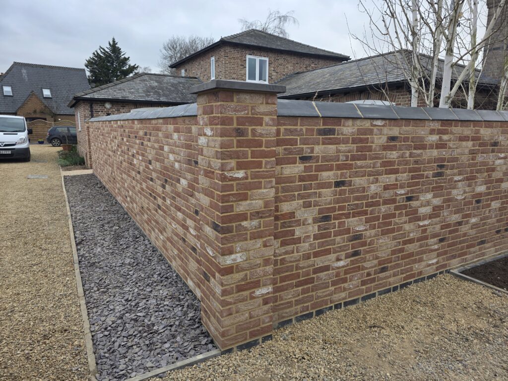 A new reddish-brown brick wall with dark grey coping