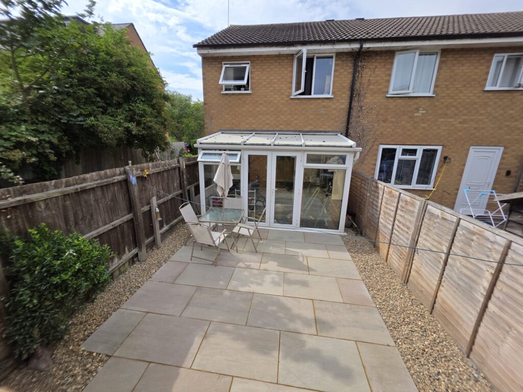 Tidy backyard patio with light grey slabs, brown fences, and gravel