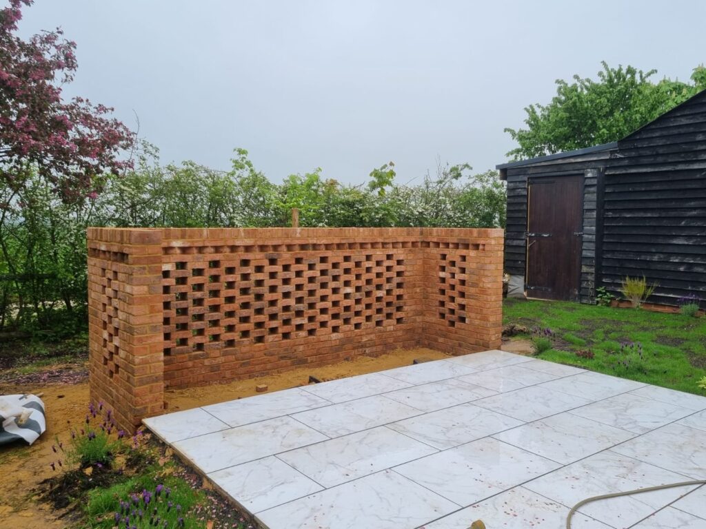 A new L-shaped brick wall with an open decorative pattern stands