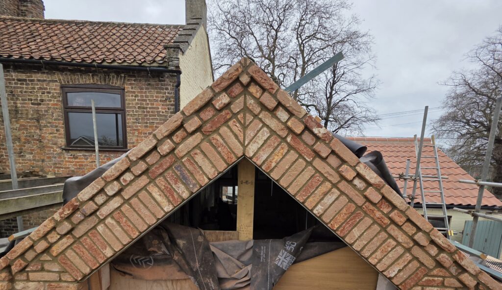 Newly built brick gable end featuring a herringbone pattern,