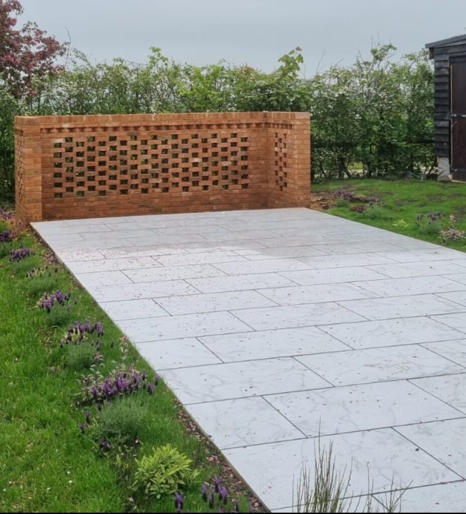 Newly installed light grey patio with a decorative reddish-