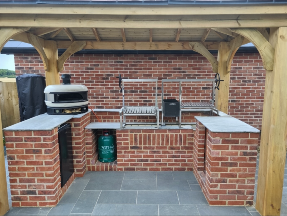 Outdoor brick kitchen with a white pizza oven, large Argentinian