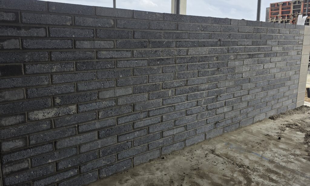 Dark gray brick wall on a construction site with concrete