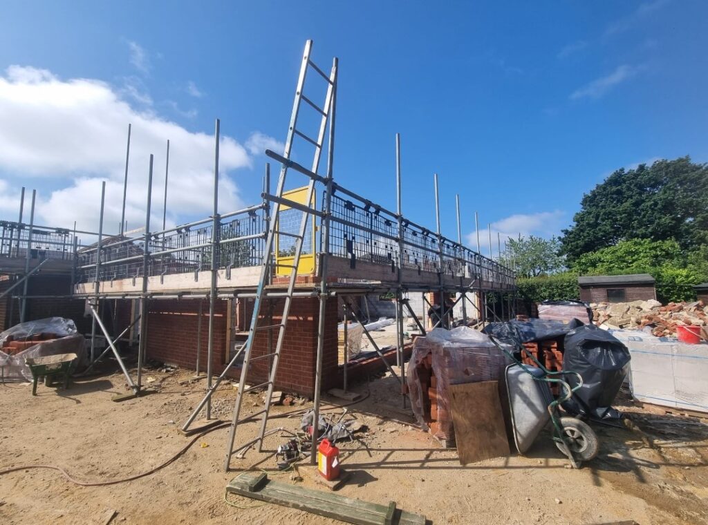 New house under construction with red brick walls, extensive scaffolding,